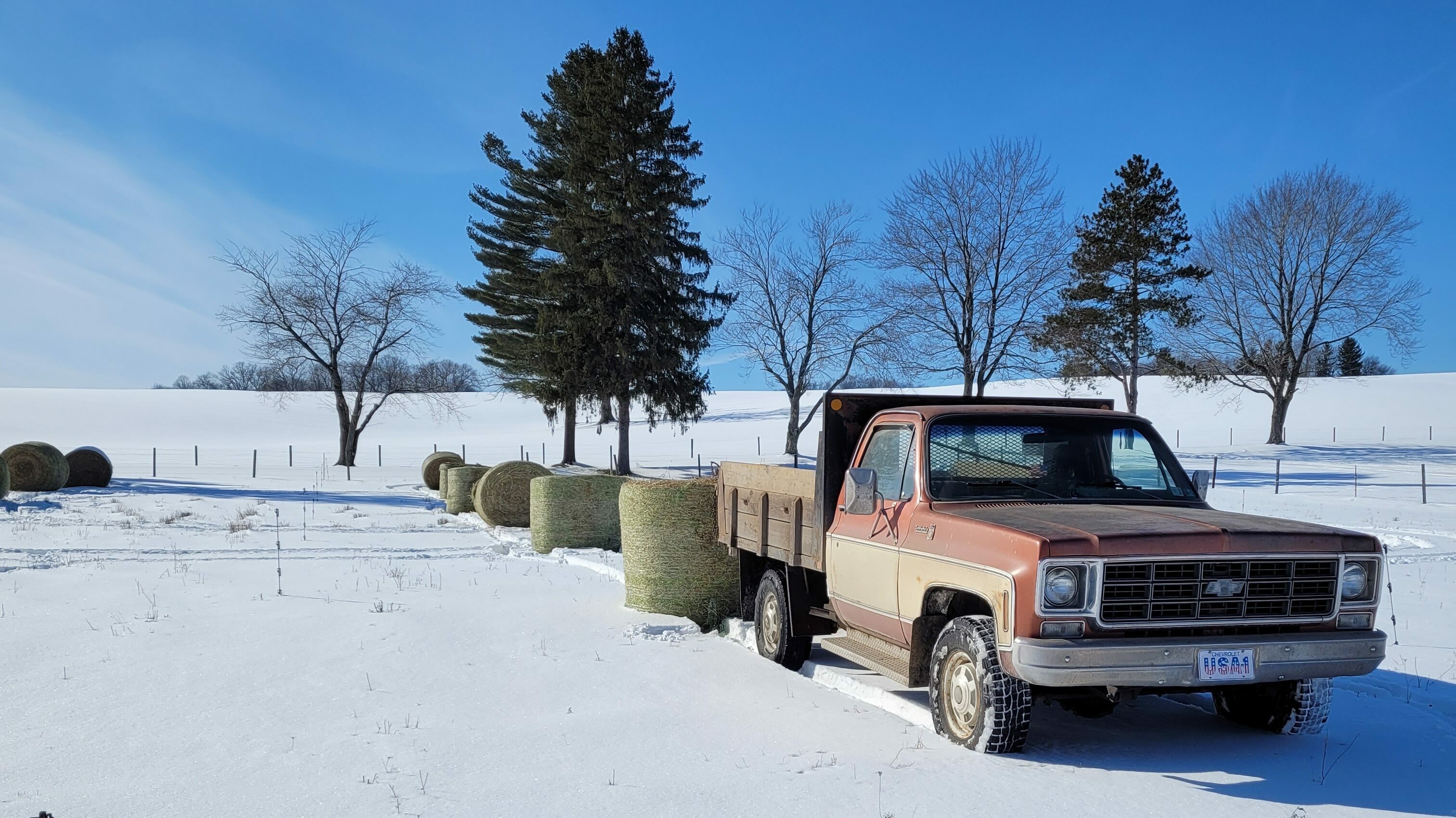 Truck in snowy field with bales
